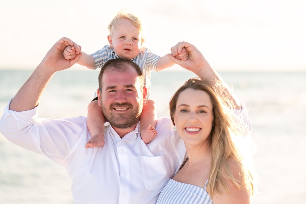 A joyful family portrait session at sunset on a white sandy beach.