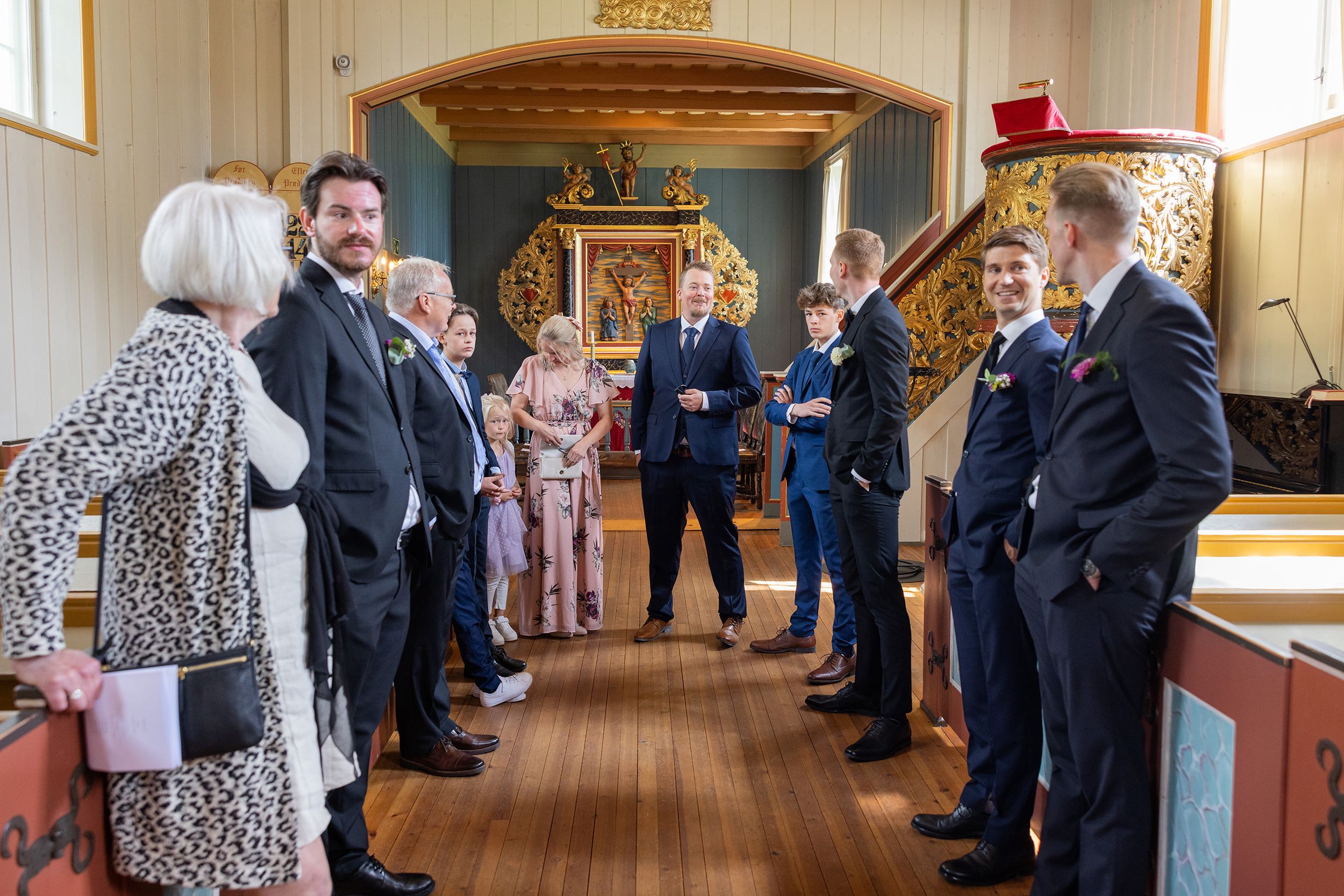 Gjester som står inne i kirken og snakker før vielsen er i gang