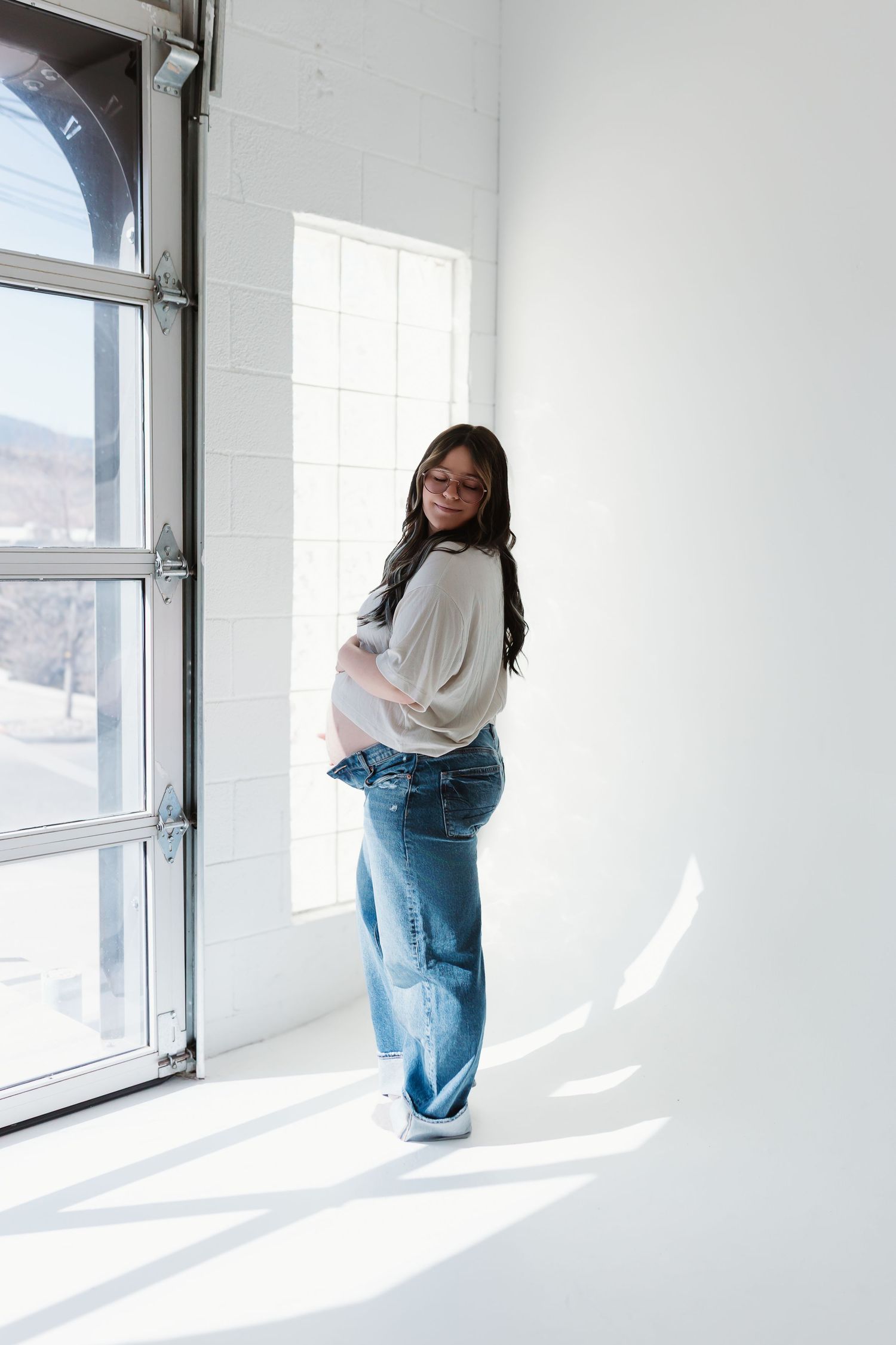 A series of four artistic black and white photos showing a figure in casual clothing against a minimalist white background.
