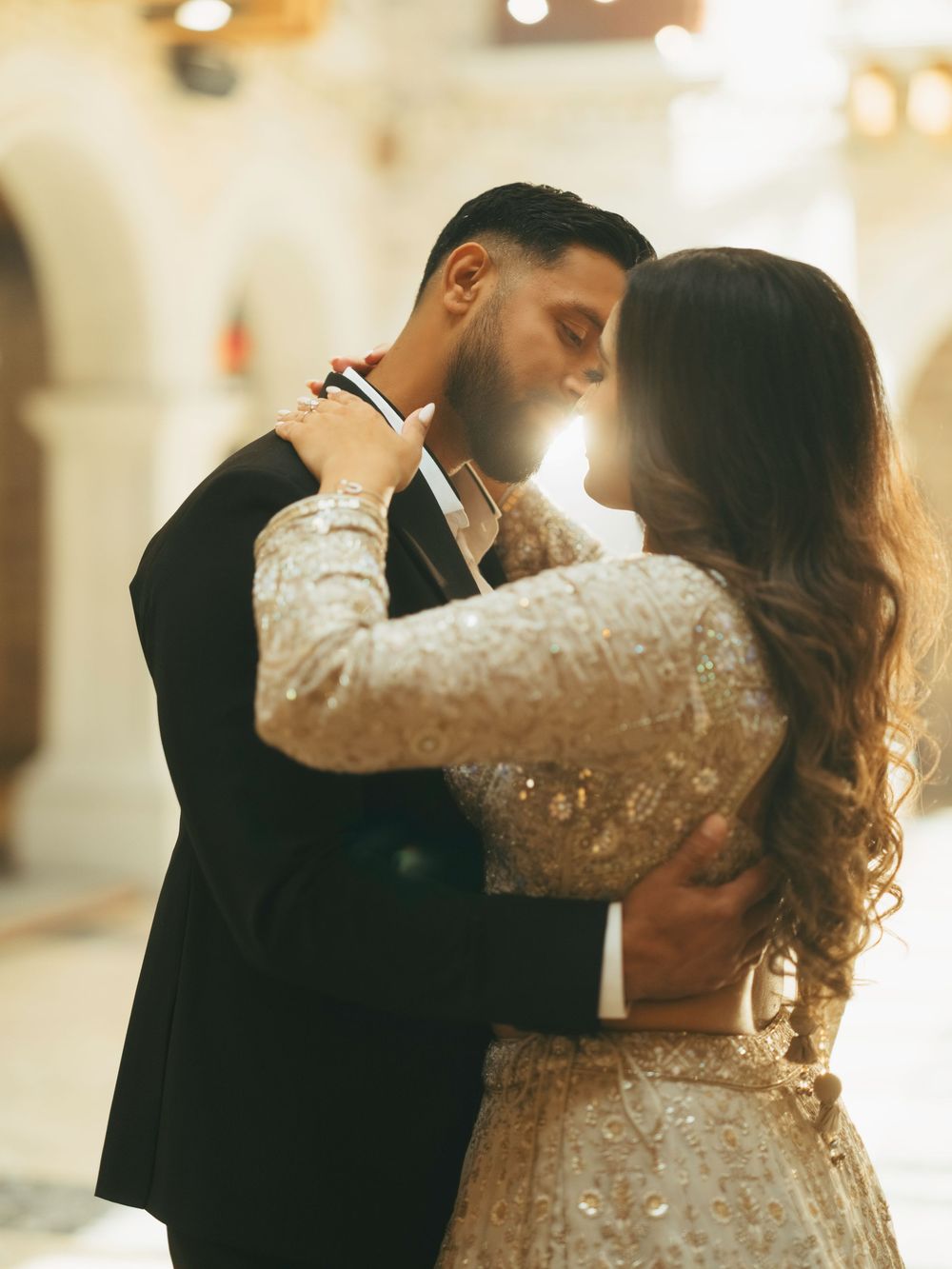 A couple in wedding attire shares an intimate dance in a warmly lit room with multiple romantic poses.