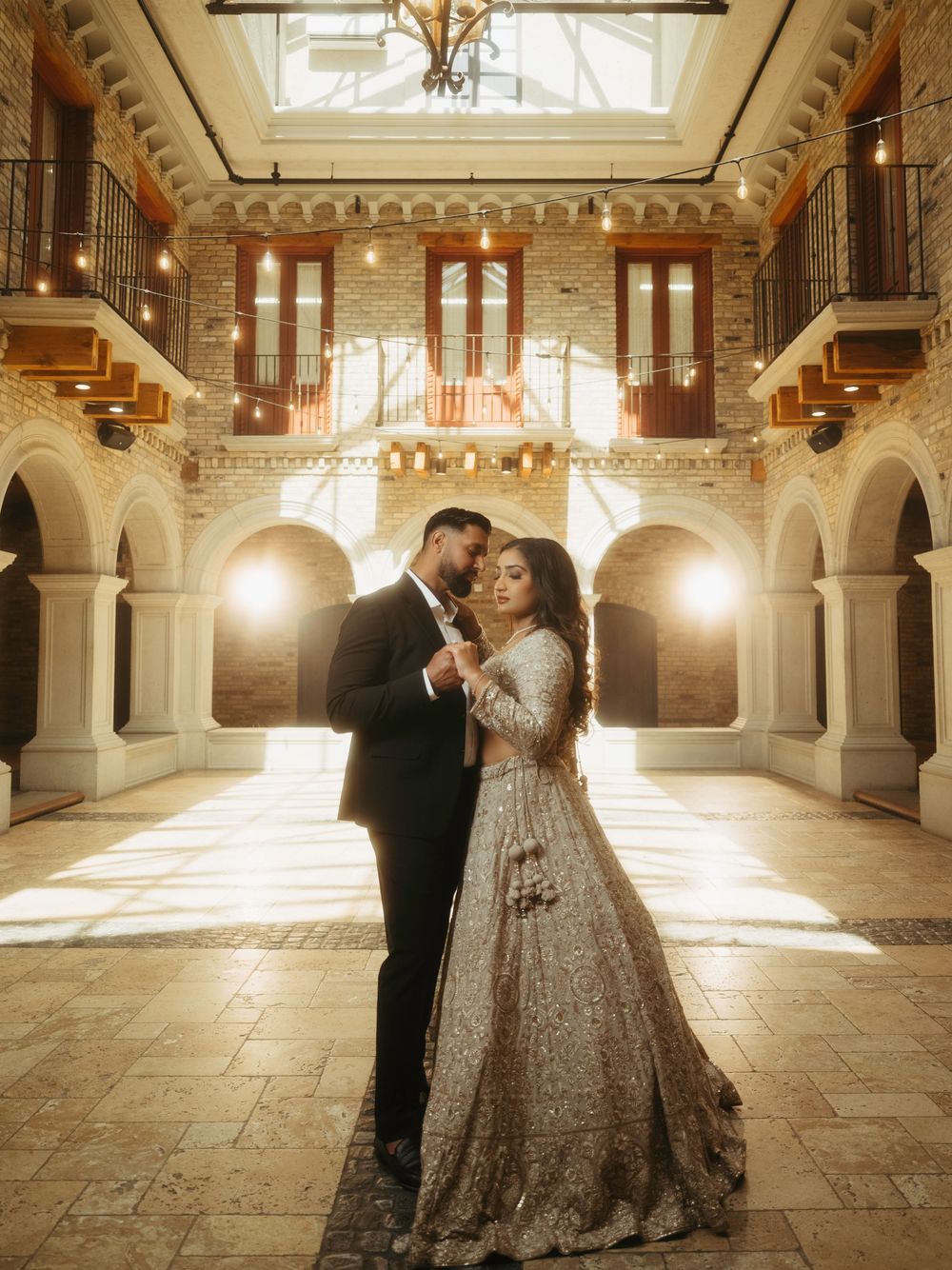 A couple dancing in an ornate historic building with grand architecture and warm lighting.