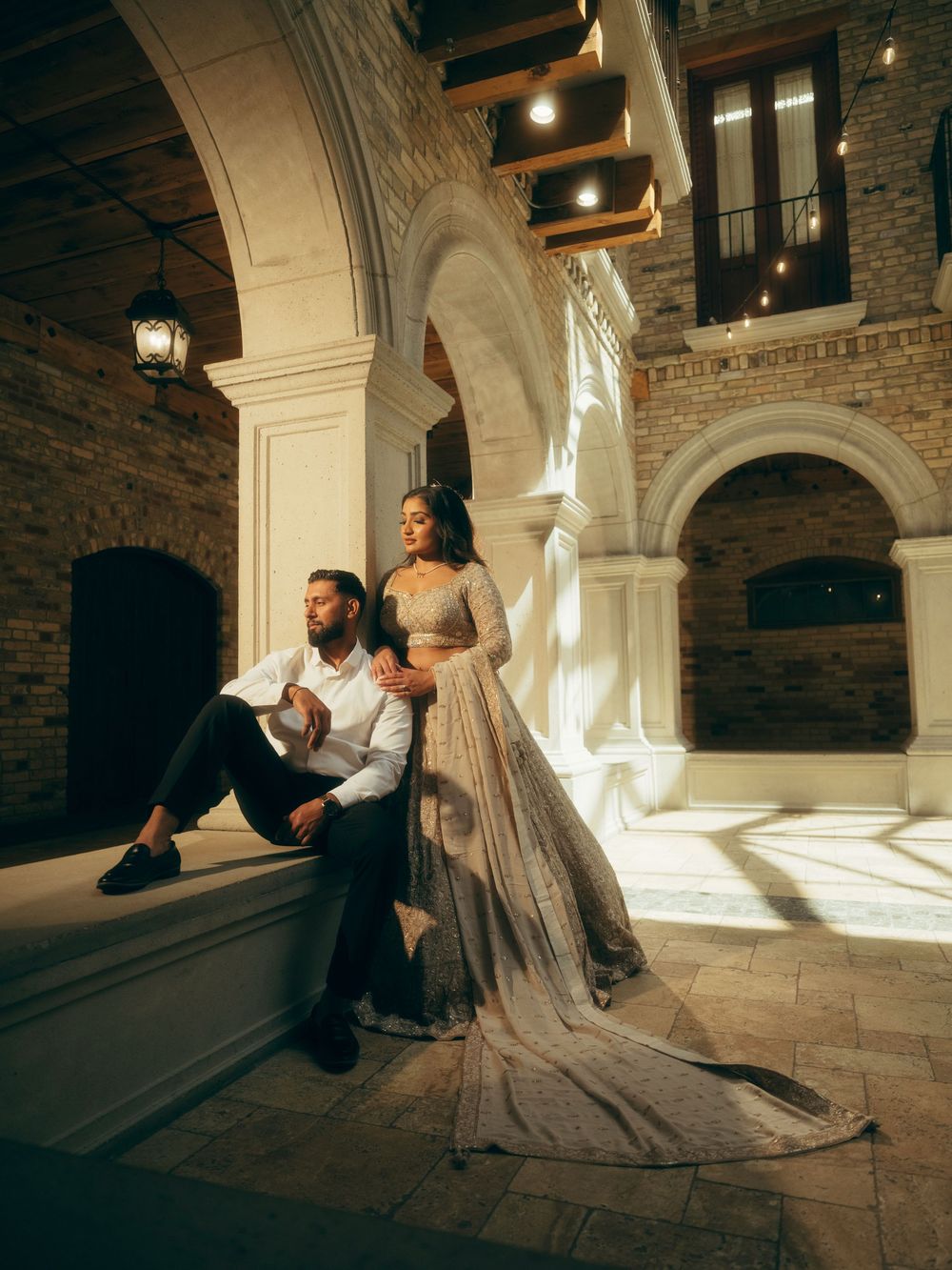 Wedding photography session under ornate stone archways with dramatic shadows and lighting.