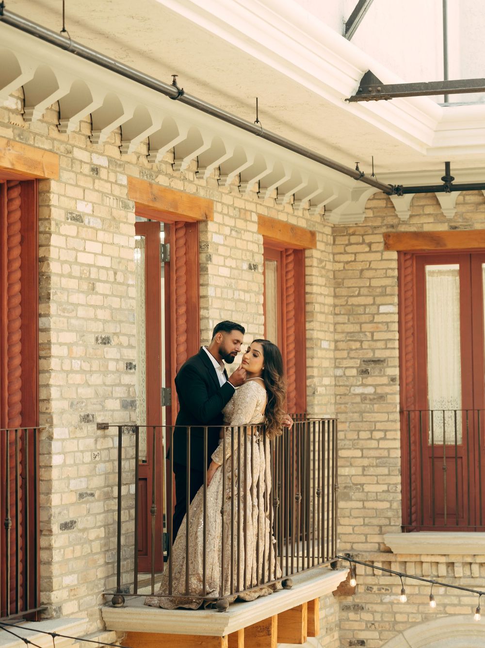 Elegant wedding photo series along a brick corridor with wooden doors and metal railings.