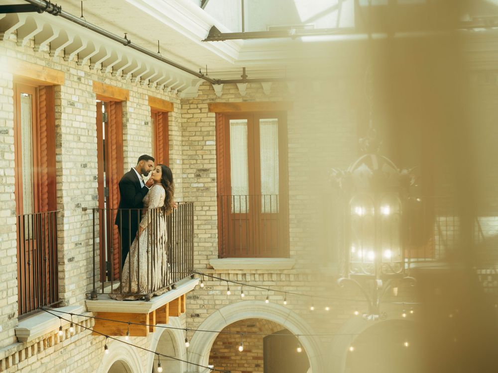 A romantic dance scene captured in a sunlit hallway with elegant stone columns and archways.