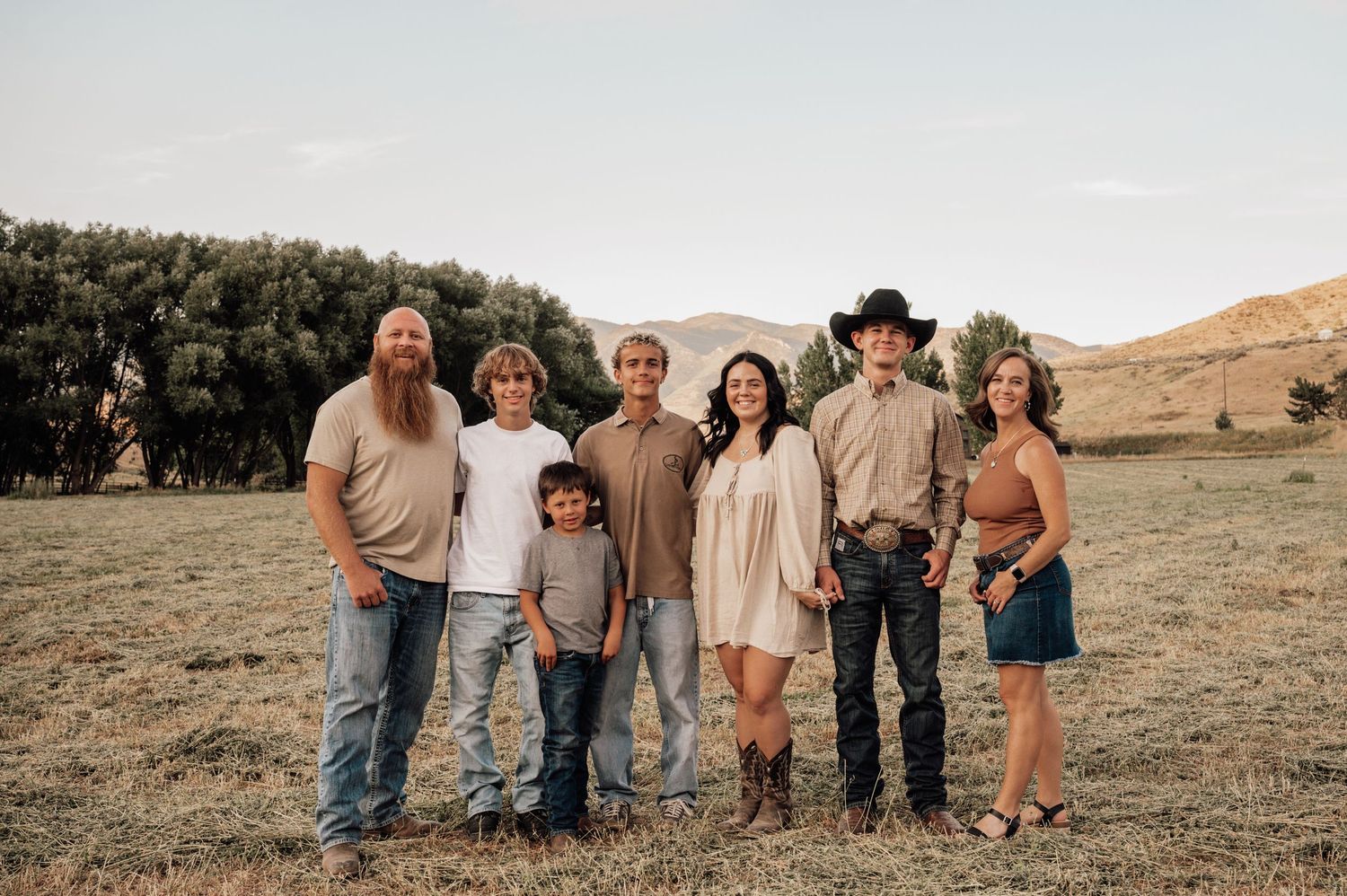 Group of people standing together on a hillside during golden hour.