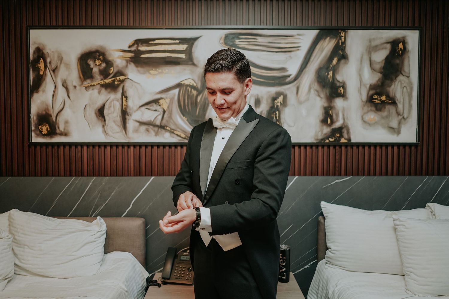 A groom in a dark suit reads handwritten vows from a piece of paper during an indoor wedding ceremony.