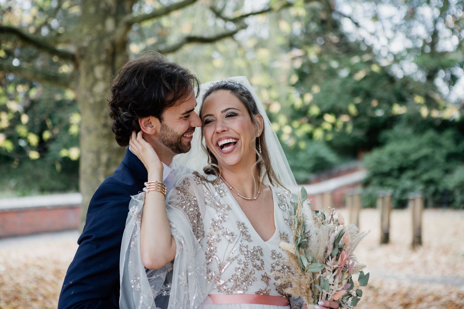 A couple shares joyful moments together in a garden setting during their wedding photoshoot.