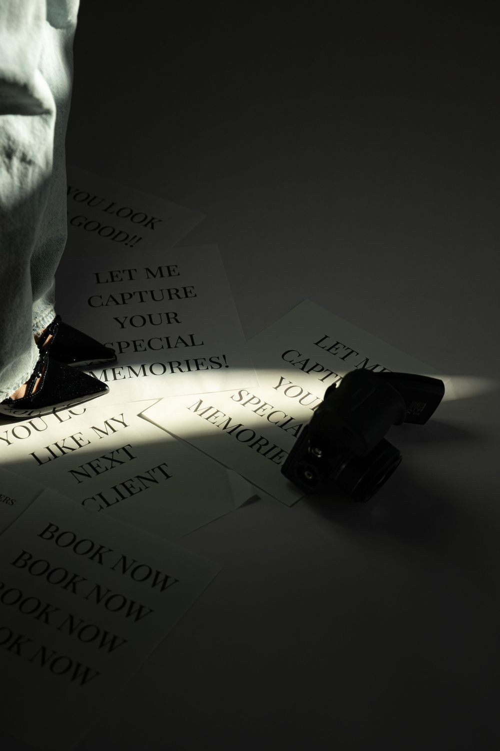 Dramatic lighting illuminates text on paper with the words 'capture' and 'book now' visible.