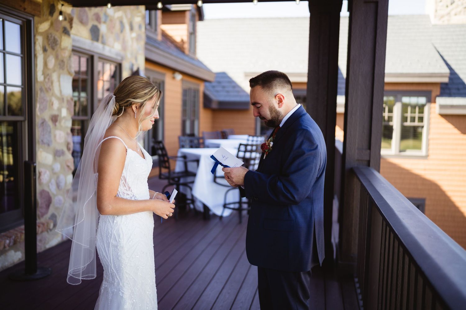 A couple shares an intimate moment on a covered porch during a wedding celebration.
