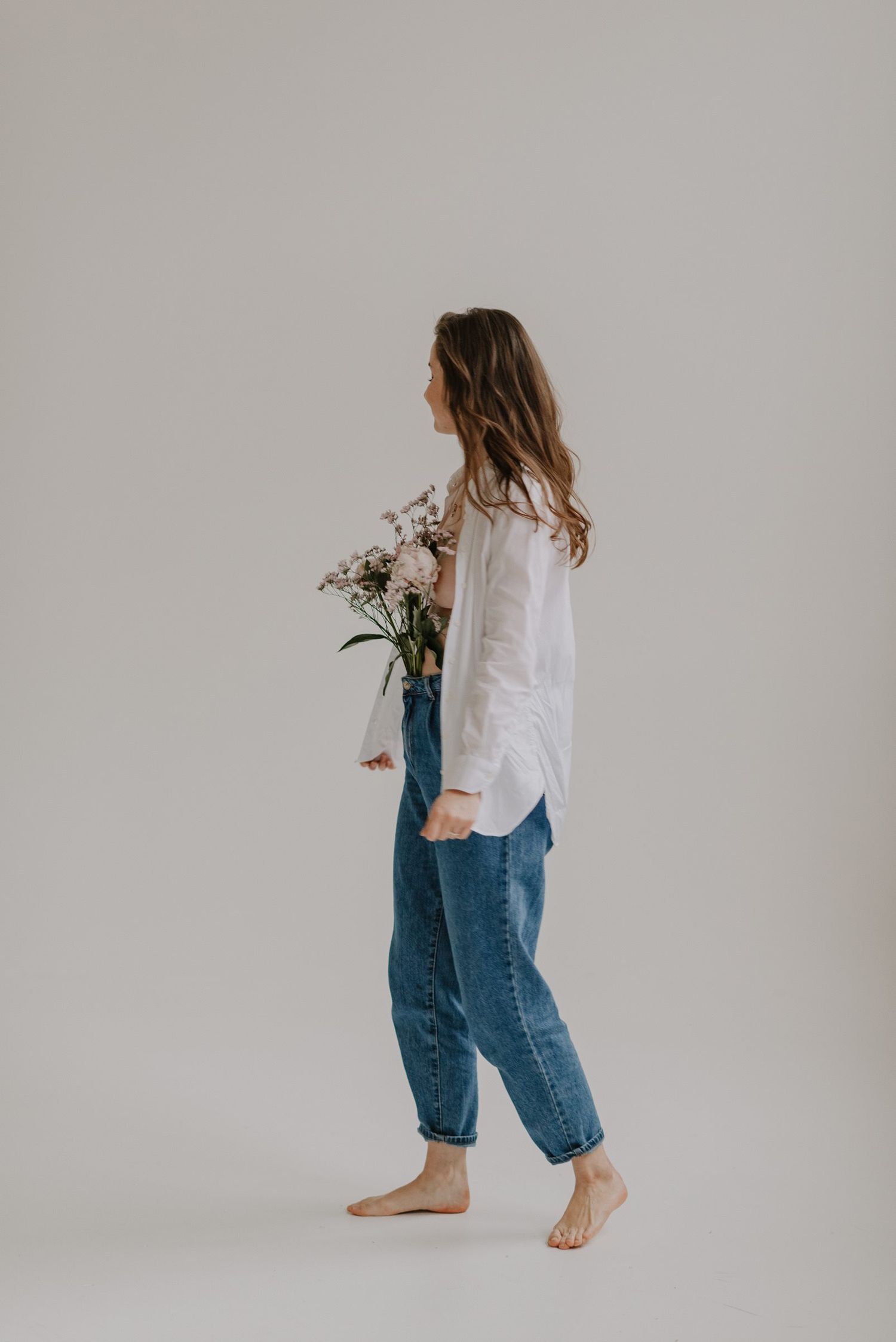 Minimalist fashion series showing movement in white shirt and relaxed jeans against light background.