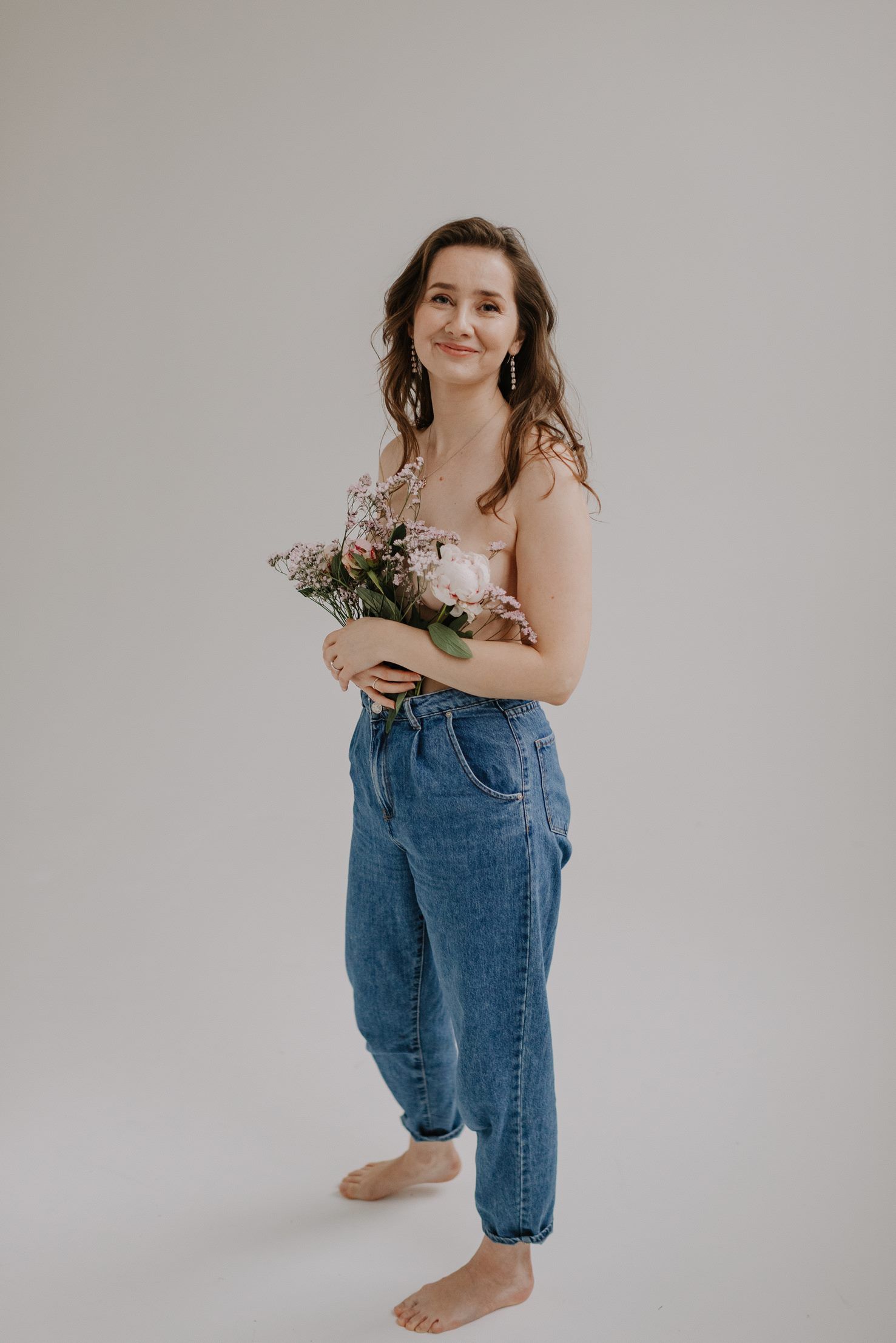 Casual studio portrait with baggy denim and delicate flowers in natural lighting.