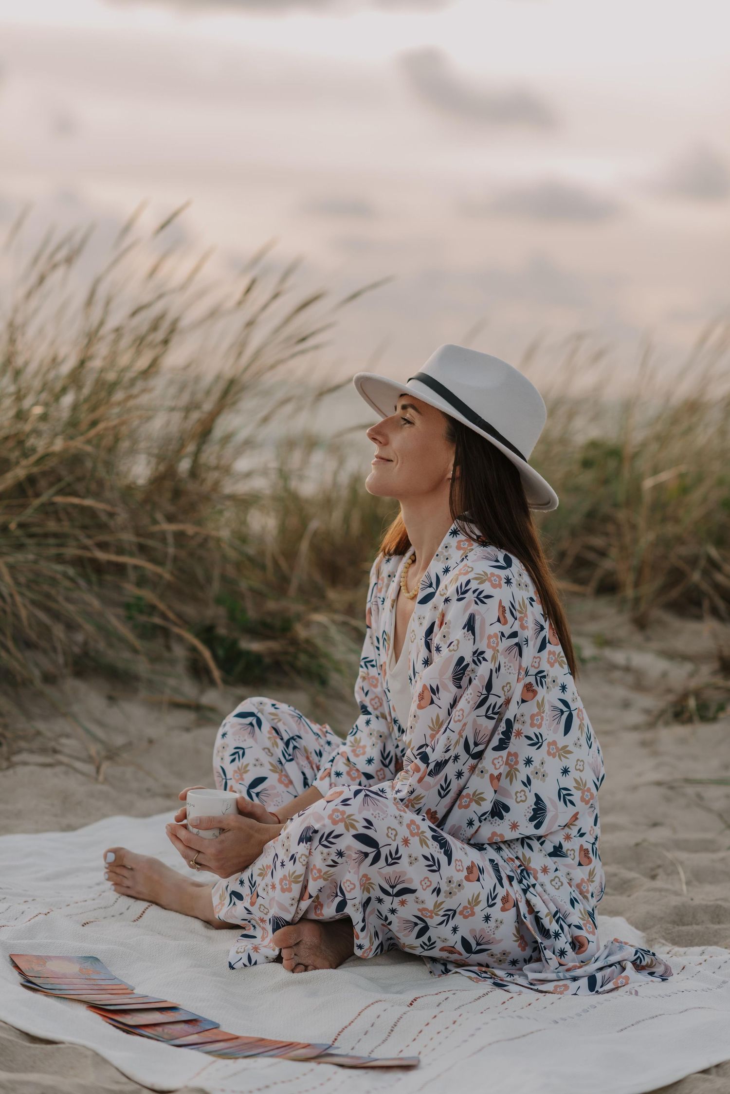 Reading peacefully on a beach blanket wearing a patterned kimono and sunhat.