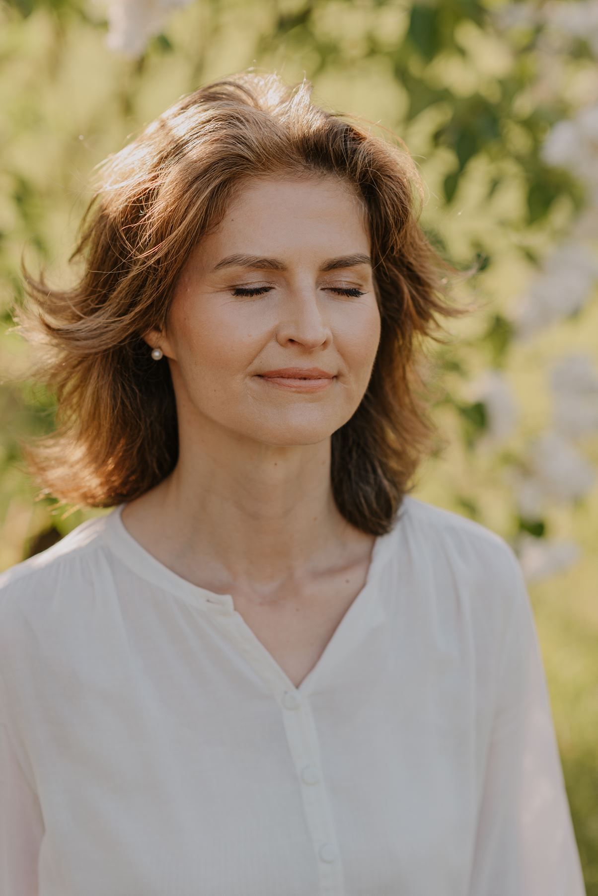 Someone in a white button-down shirt enjoys a peaceful moment in golden afternoon light.