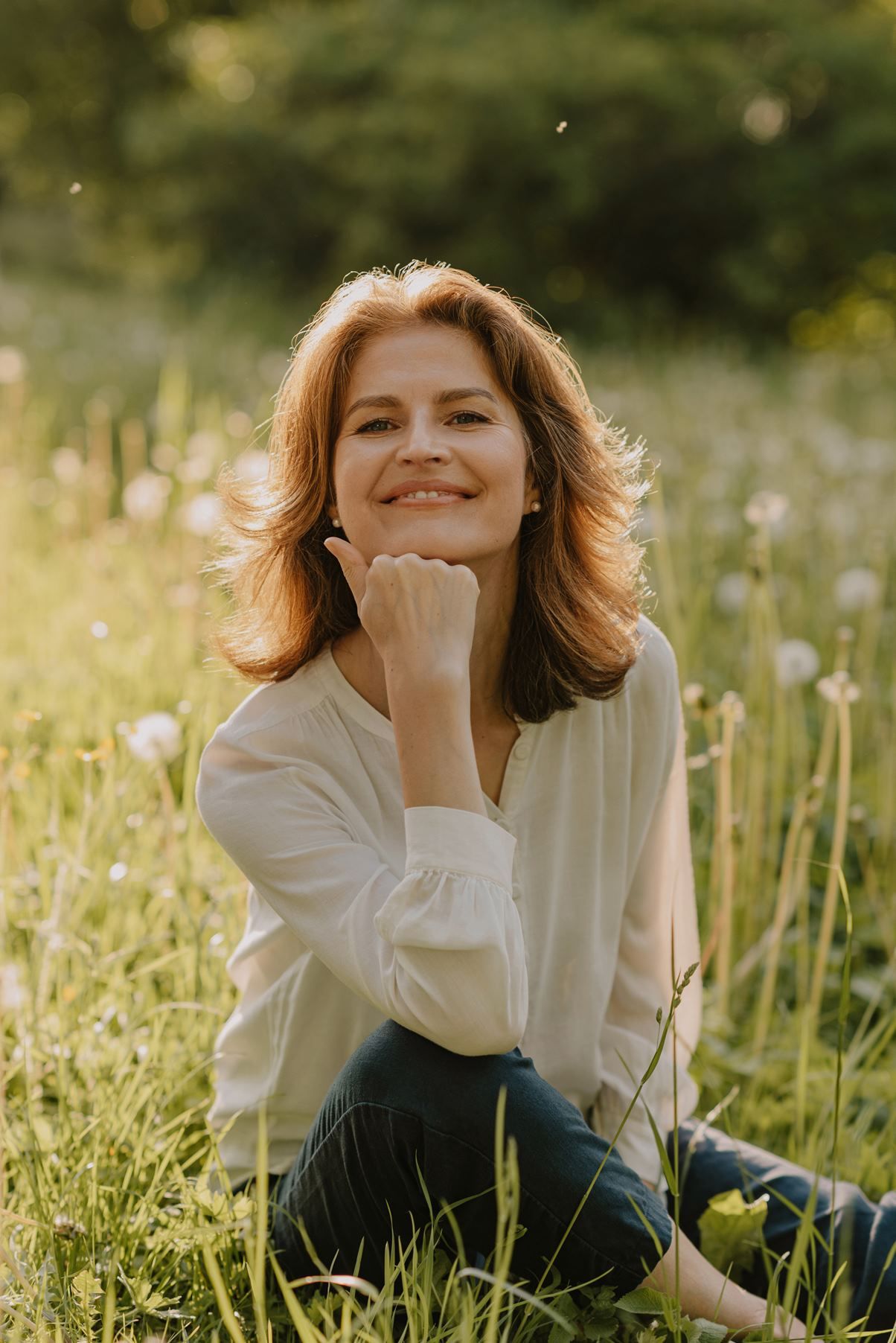 A person in a white shirt relaxes in a sunny meadow filled with wildflowers.