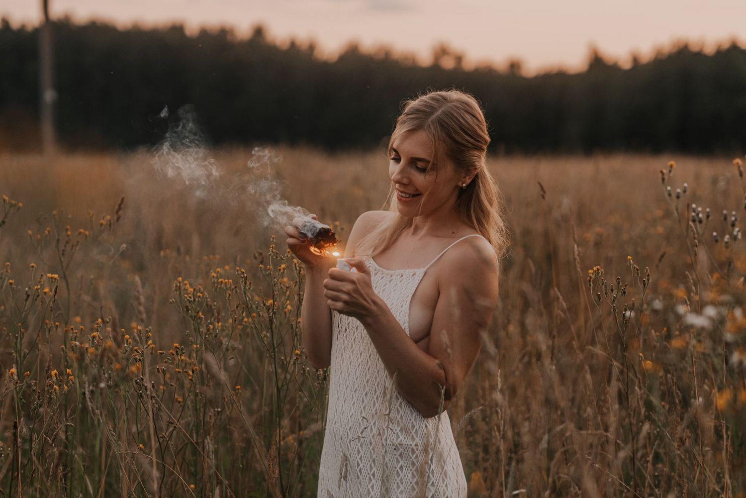 Woman walking through golden wheat field at sunset in flowing dress.