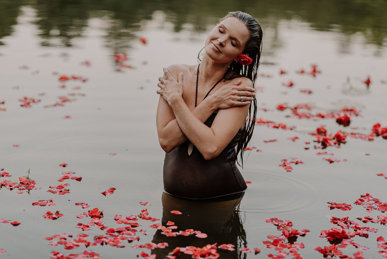 Artistic water portrait with floating red rose petals creating romantic atmosphere.