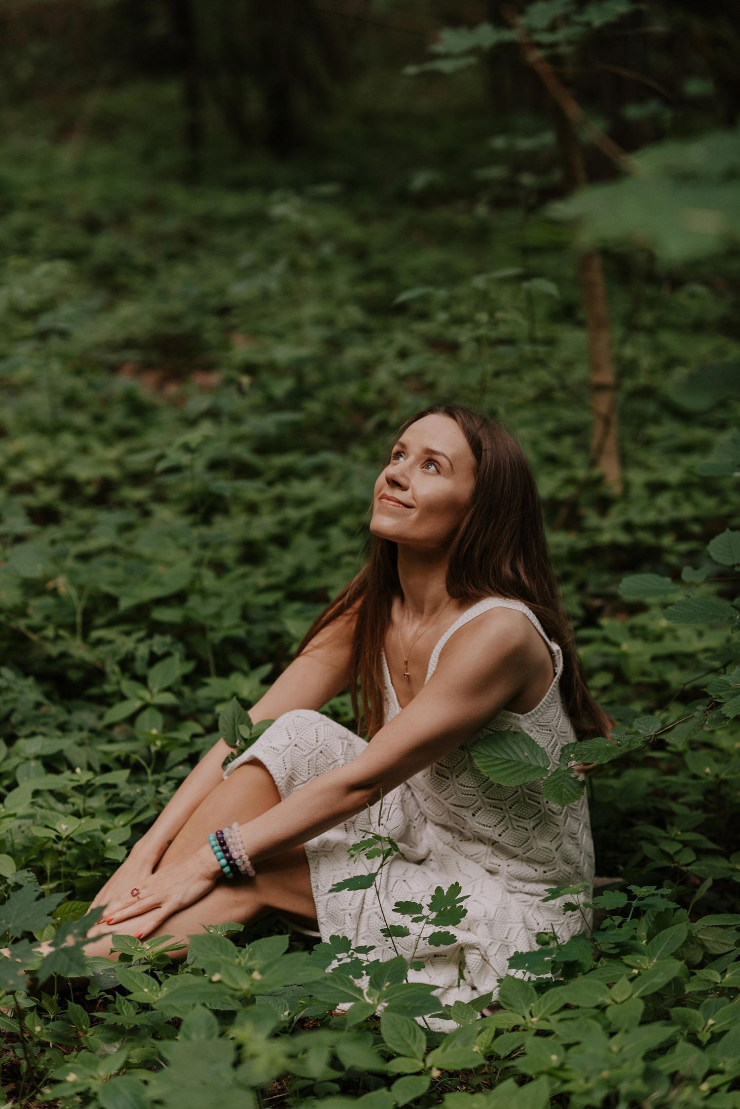 Artistic portrait of someone resting in a bed of lush green leaves and plants.