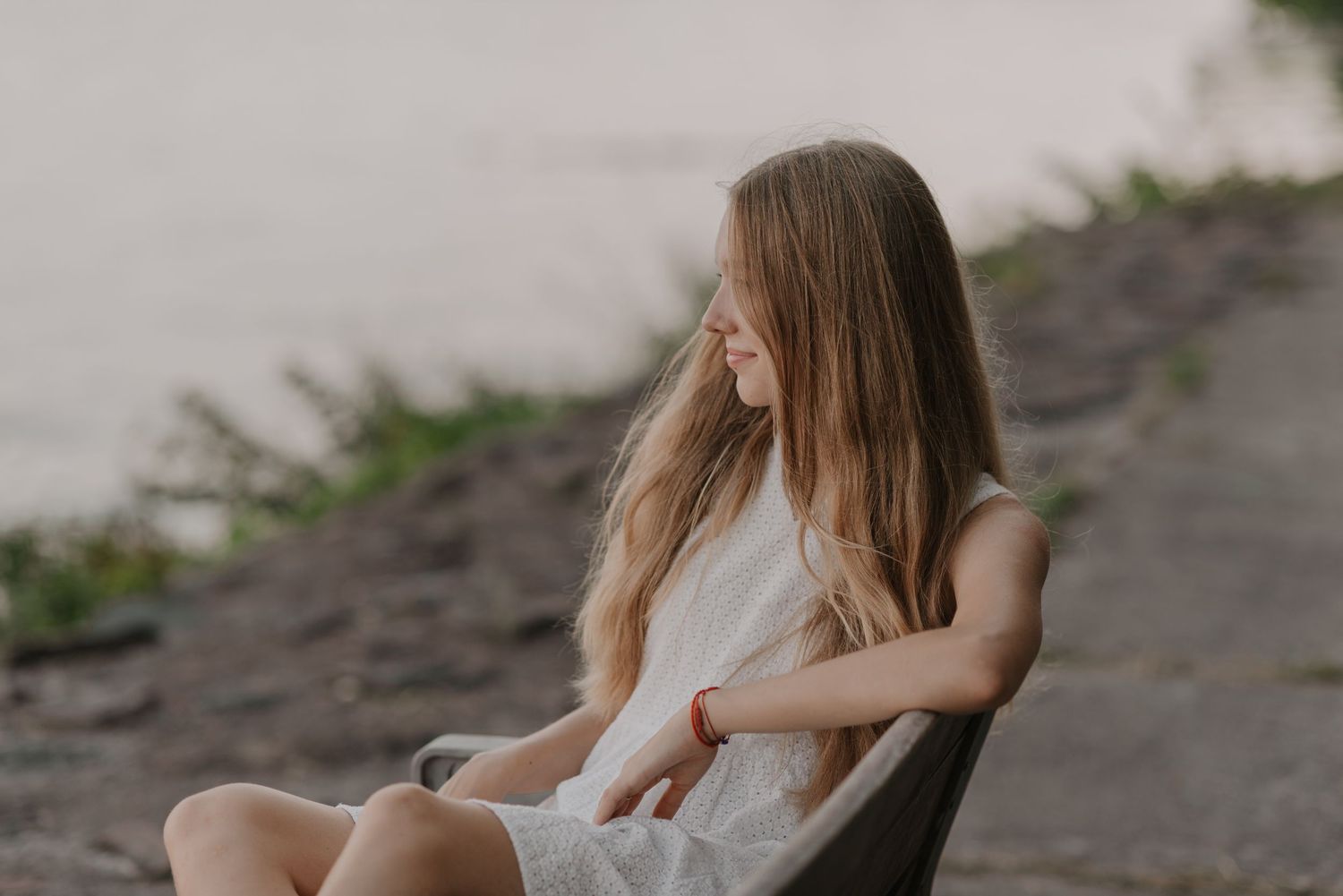 Woman in white dress relaxing by waters edge.
