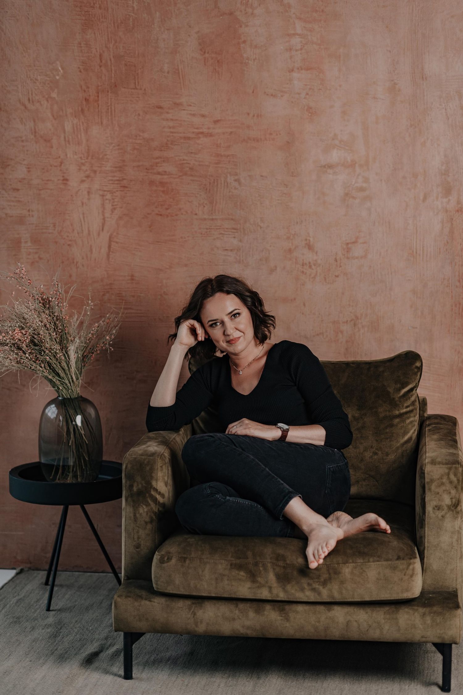 Lifestyle portrait of someone relaxing on a brown velvet couch with minimalist decor.