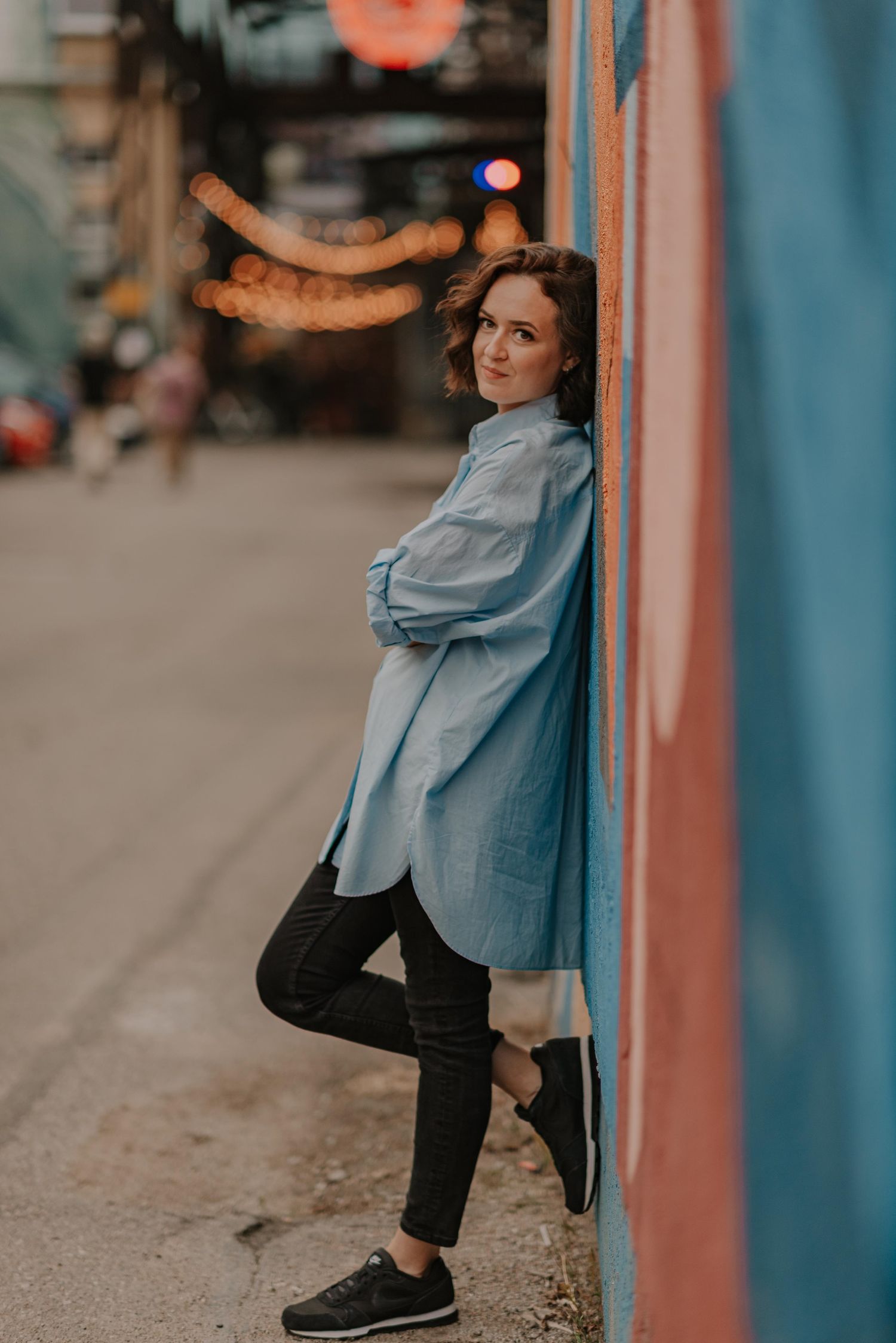 Urban portrait against blue wall showing movement and casual style.