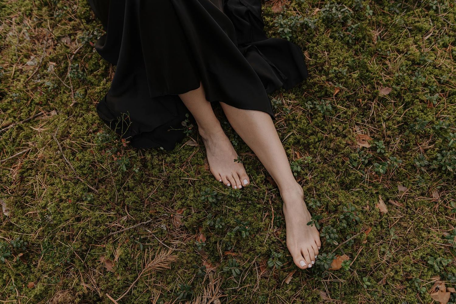 Close-up shots of bare feet on moss-covered forest ground.