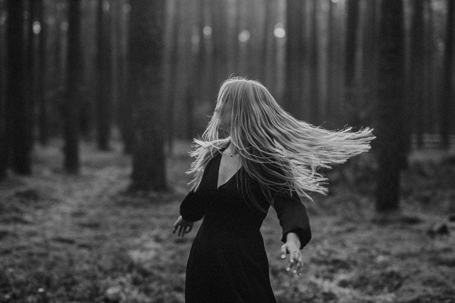 Someone spins through a misty forest with hair flowing in the motion.