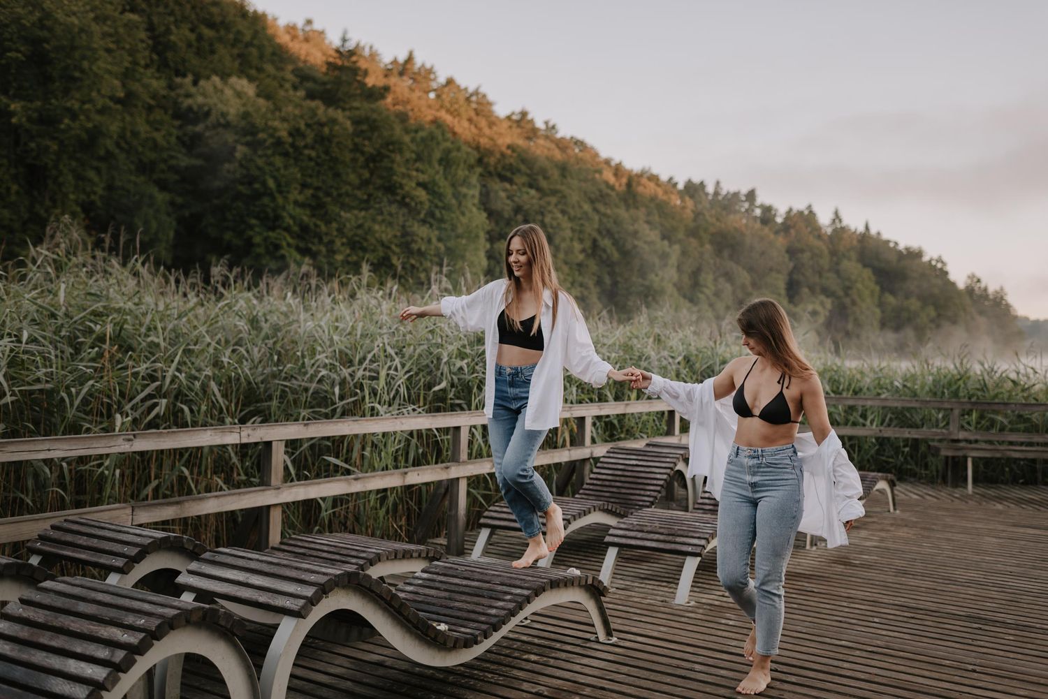 Friends enjoying a casual stroll along a wooden boardwalk with mountains in the background.