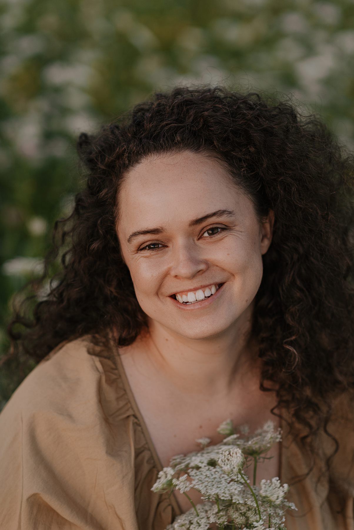 A joyful portrait with white flowers and natural lighting in an outdoor setting.