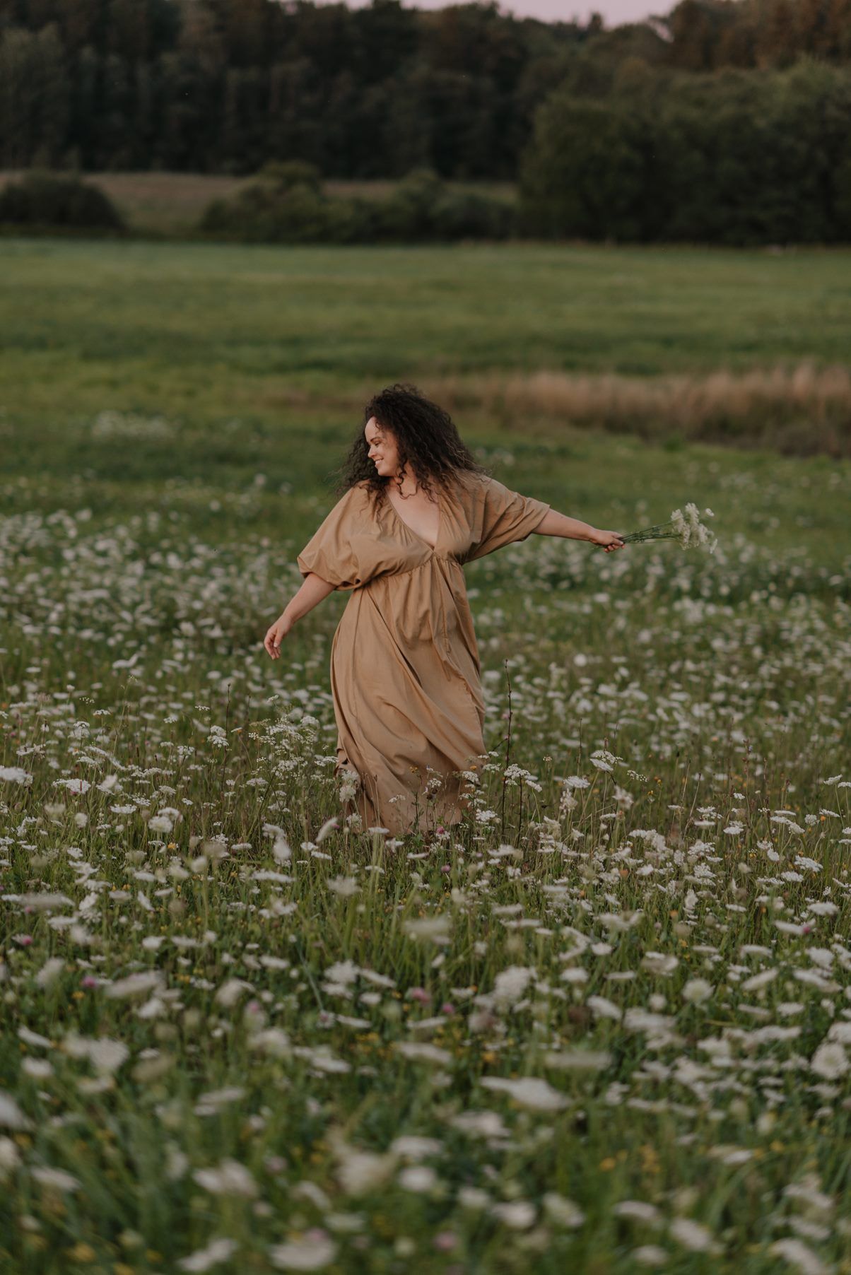 Dreamy scene of someone dancing through a meadow of white flowers at dusk.