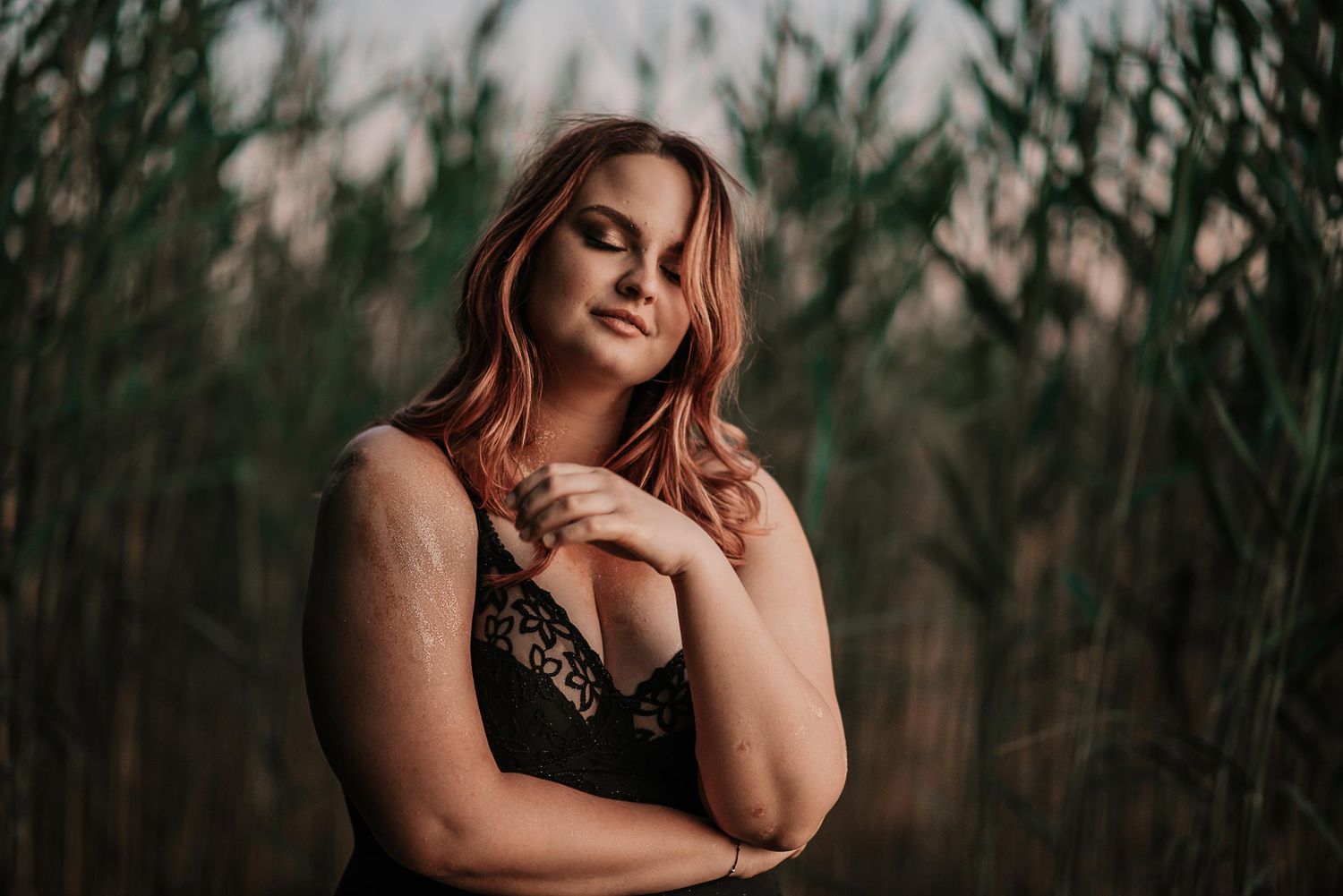 Artistic portrait photoshoot in dark moody outdoor setting with natural lighting.