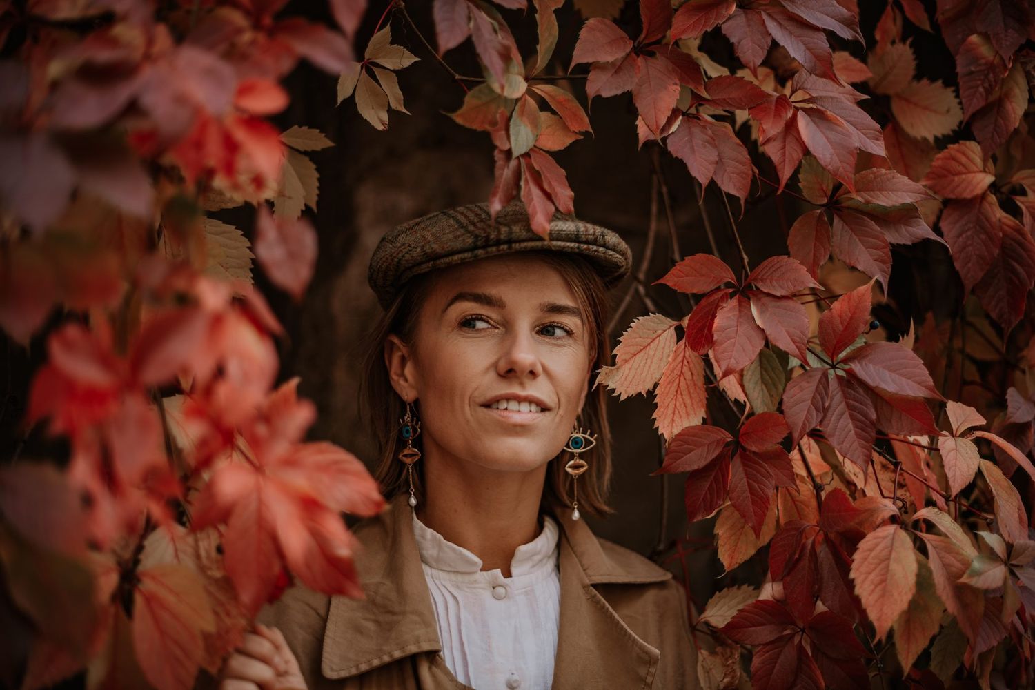 Portrait against wall of red autumn leaves creating dramatic natural backdrop.