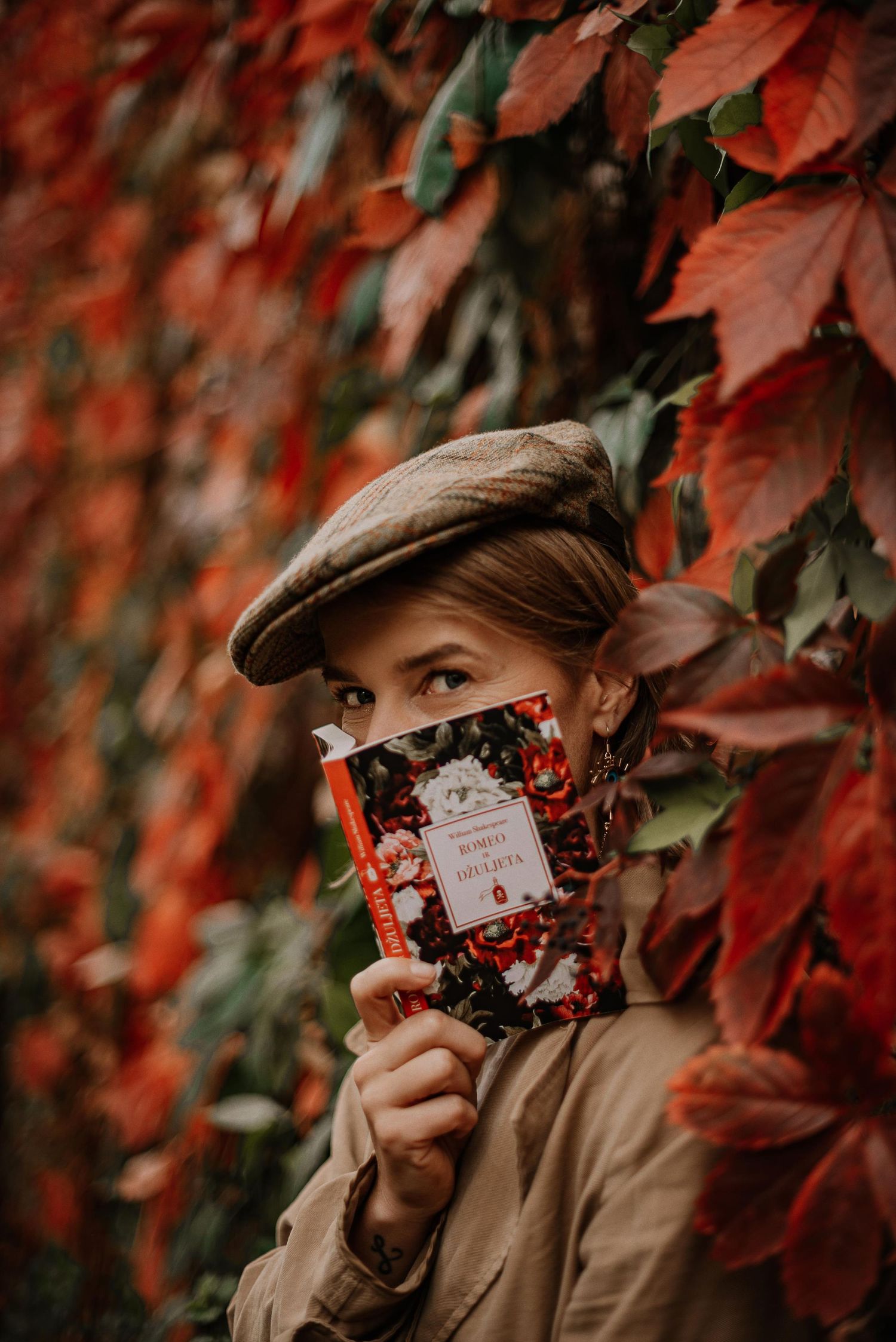 Artistic autumn photo with deep red foliage and vintage camera against moody background.