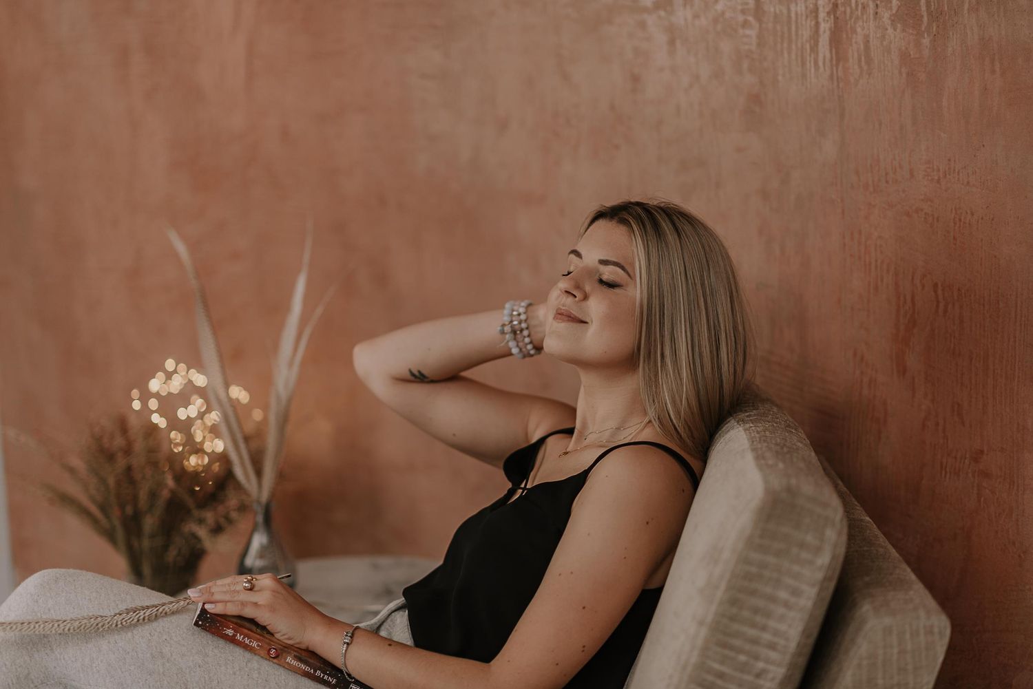 Cozy indoor portrait against terracotta wall with dried flowers and natural styling.