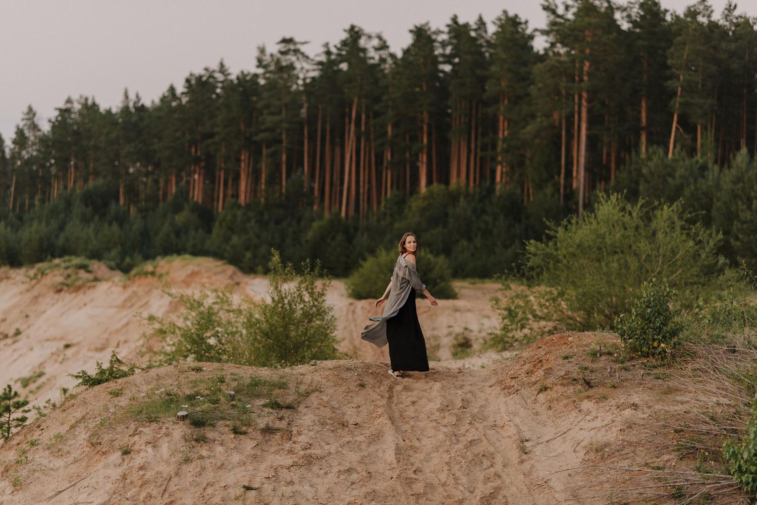 Sandy dunes and pine trees create a natural outdoor setting.