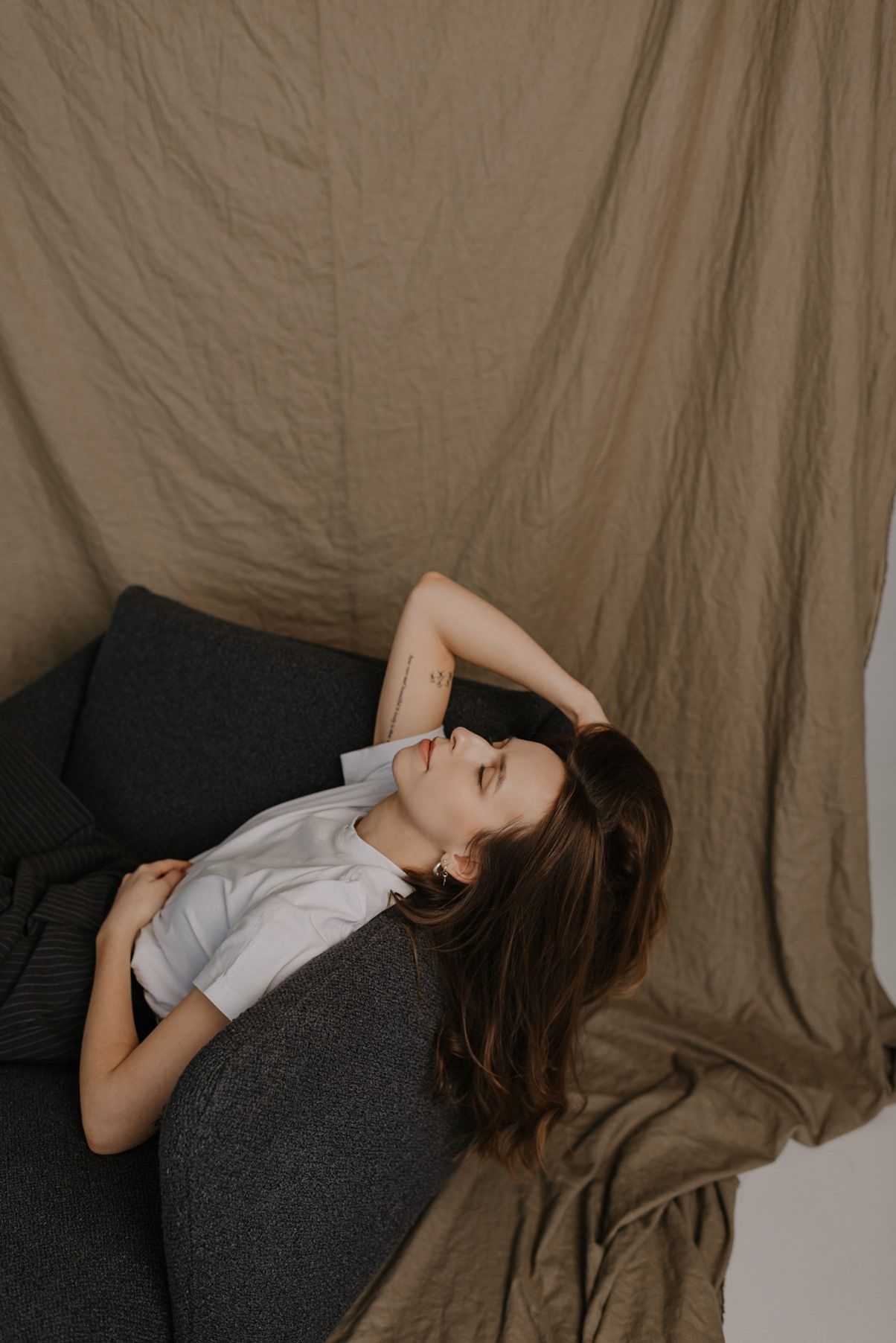 Moody portrait session with soft lighting against textured fabric background.