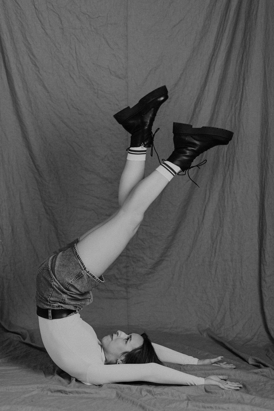 Artistic black and white portrait with dramatic poses against fabric backdrop.