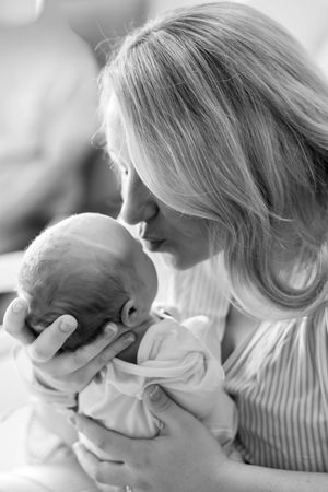 Mom kissing newborn baby at hospital 48 hours after giving birth.