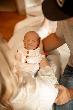 A fresh 48 session, image of infant in parents arms at the hospital after delivery