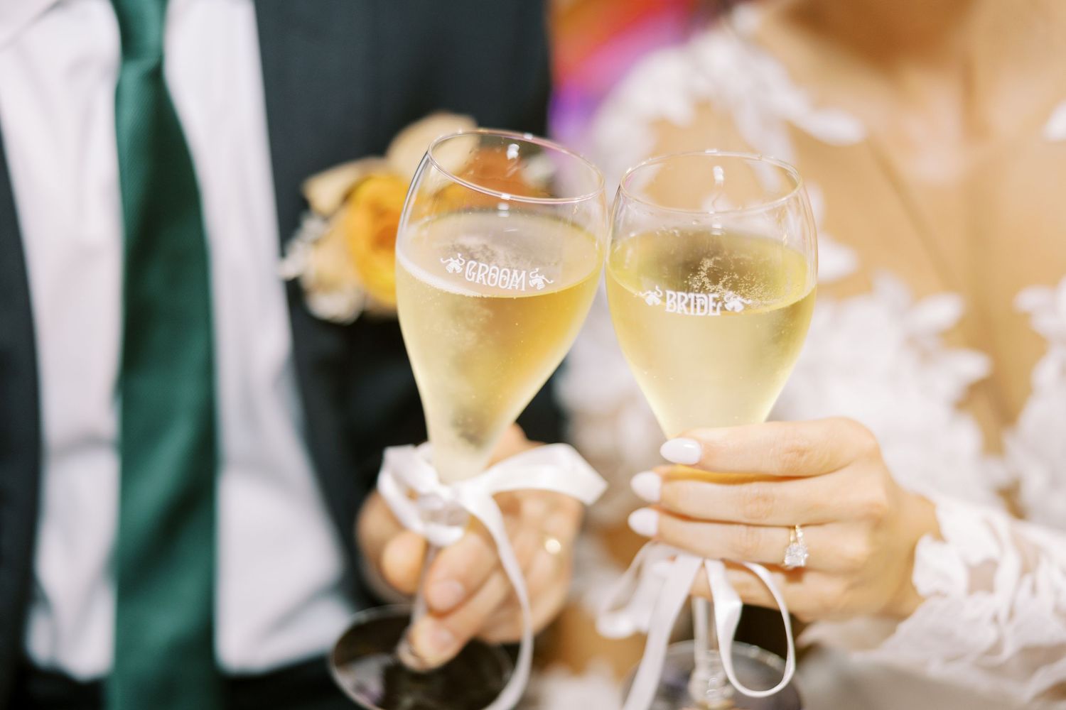 Crystal wine glasses filled with sparkling champagne reflect light against a blurred background at an elegant event.