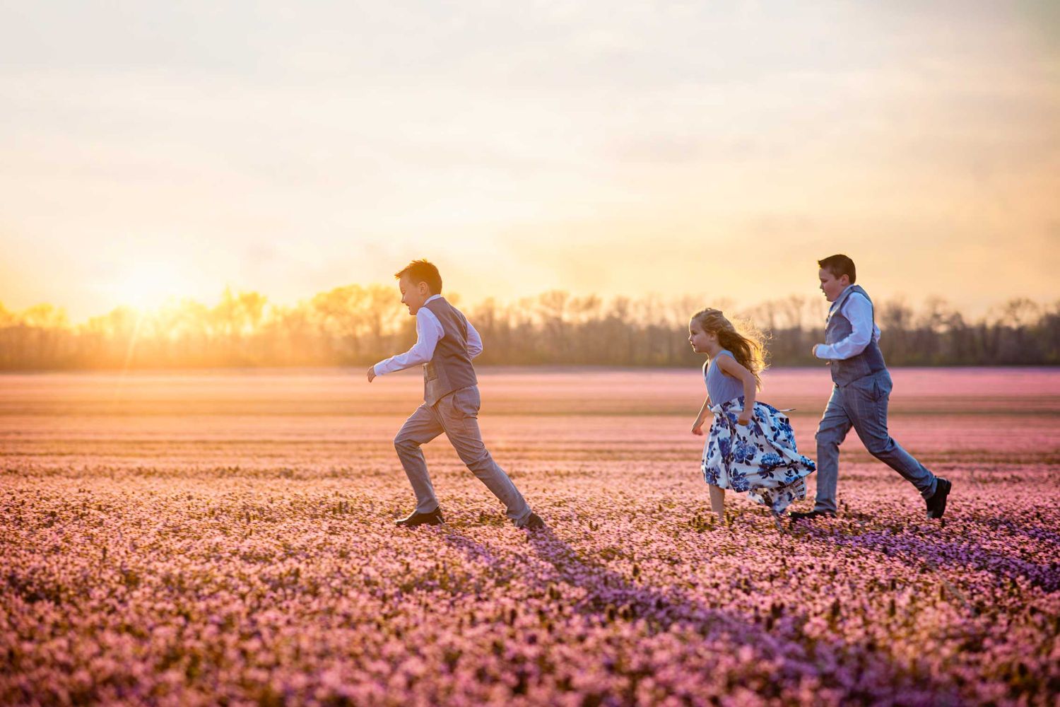 People running through a beautiful purple flower field at golden hour.