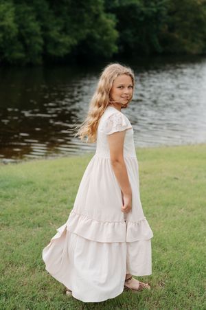White flowy dress creates movement across a grassy lakeside setting in a series of artistic shots.