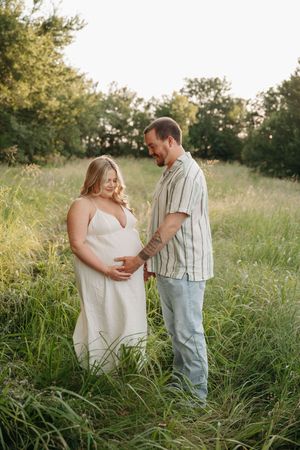 Couple shares tender moments together in tall grass during golden hour.