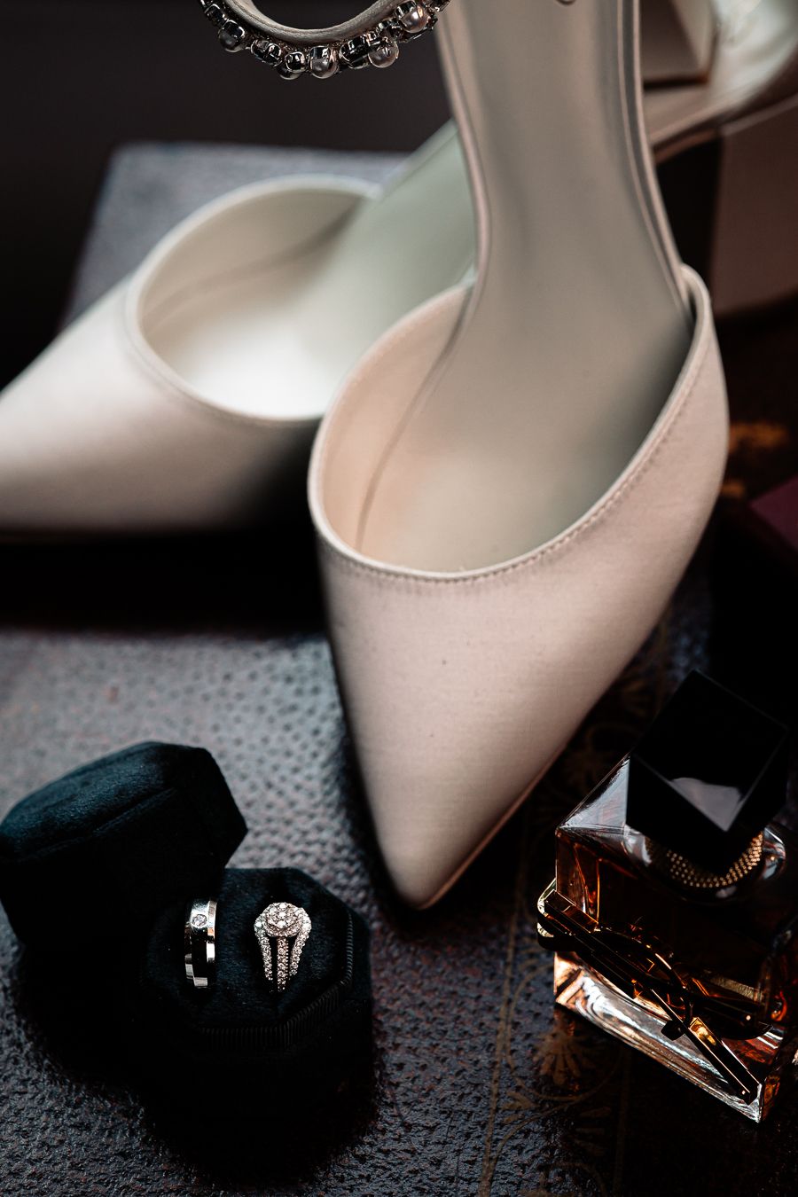 Elegant wedding details: bridal shoes, rings, and perfume.
