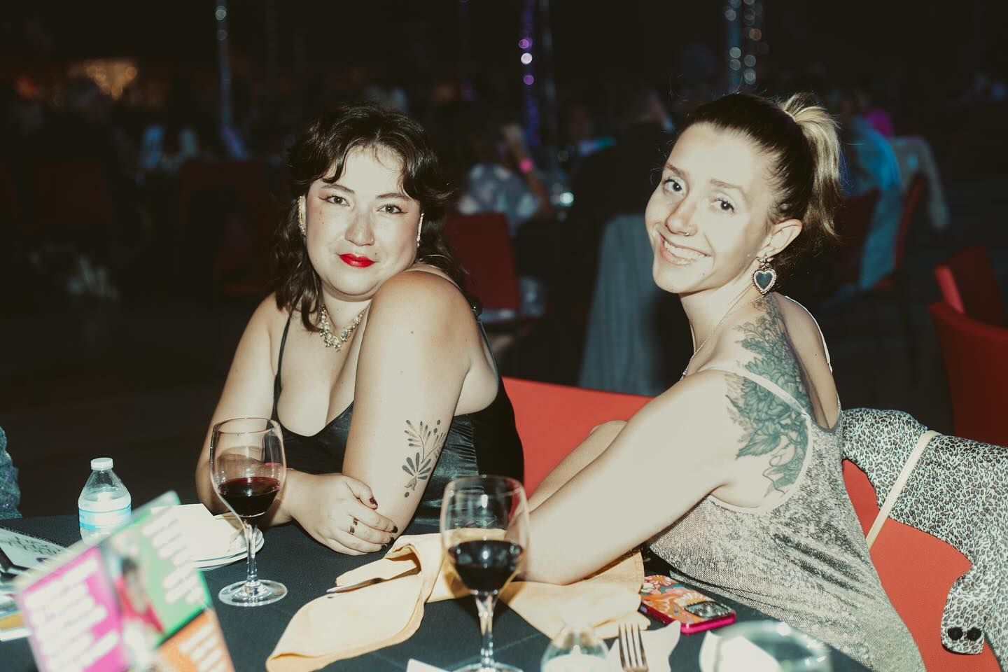 Two women sitting together pose at table.