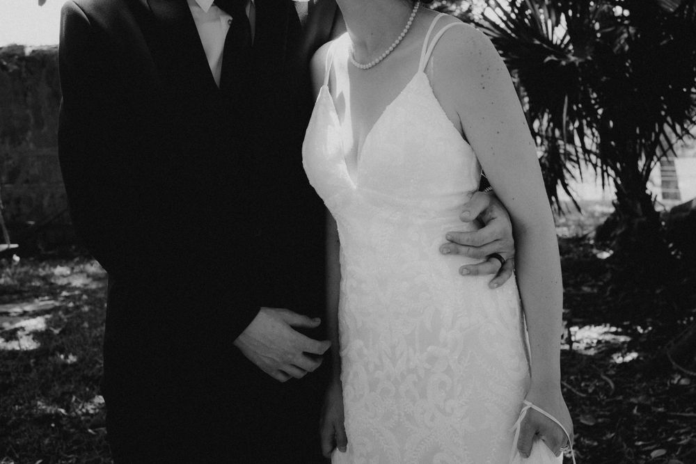 Intimate black and white portrait of newlyweds in formal attire.