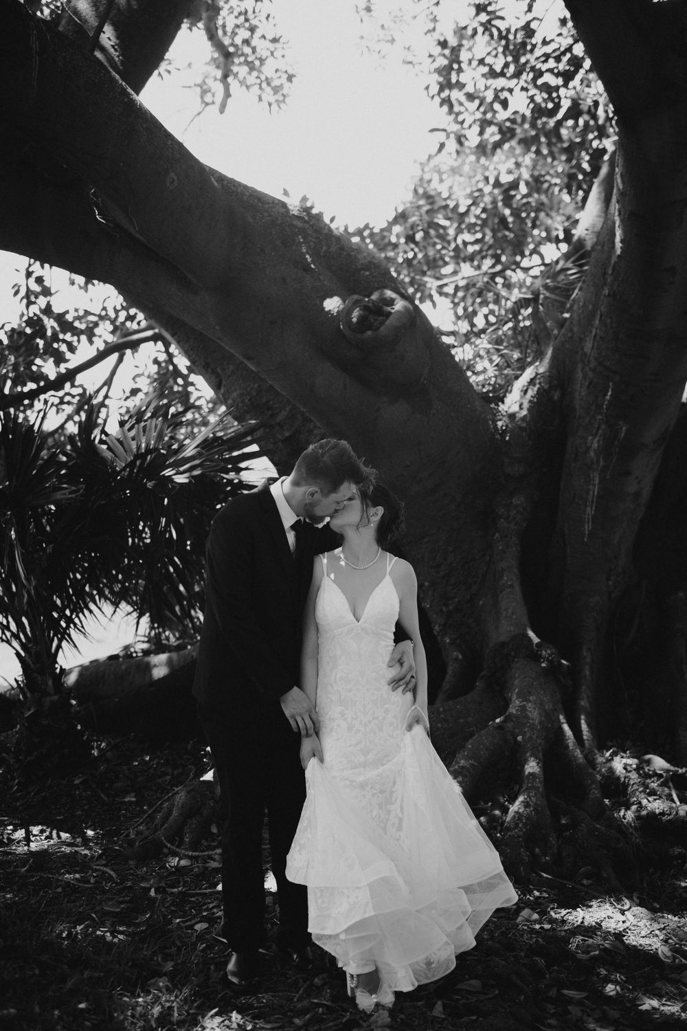 Black and white images of a white dress flowing in a garden setting with dramatic tree shadows.