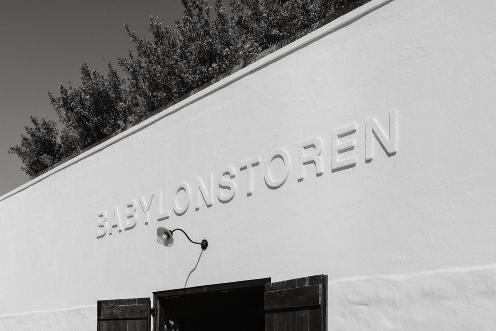 A black and white image shows 'FAEMONSTOREN' text mounted on a white building wall with a small security light below.