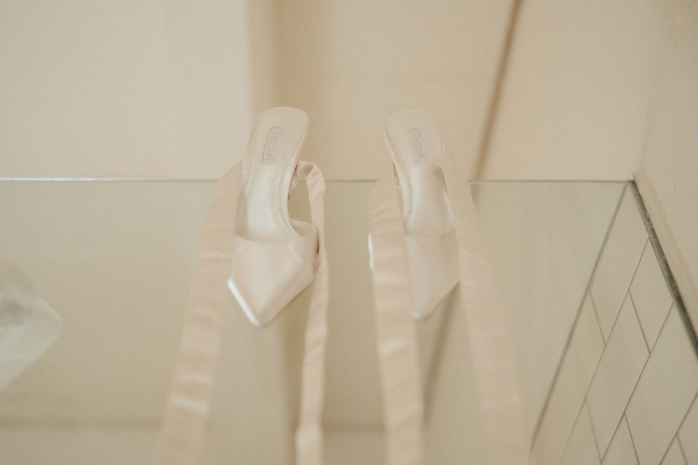 Clear glass high heel shoes displayed on reflective surface.