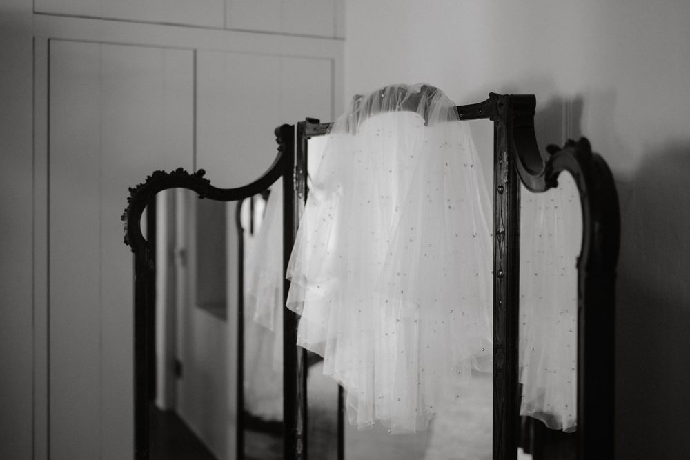 White veil or fabric draped over ornate black vintage mirror frame.