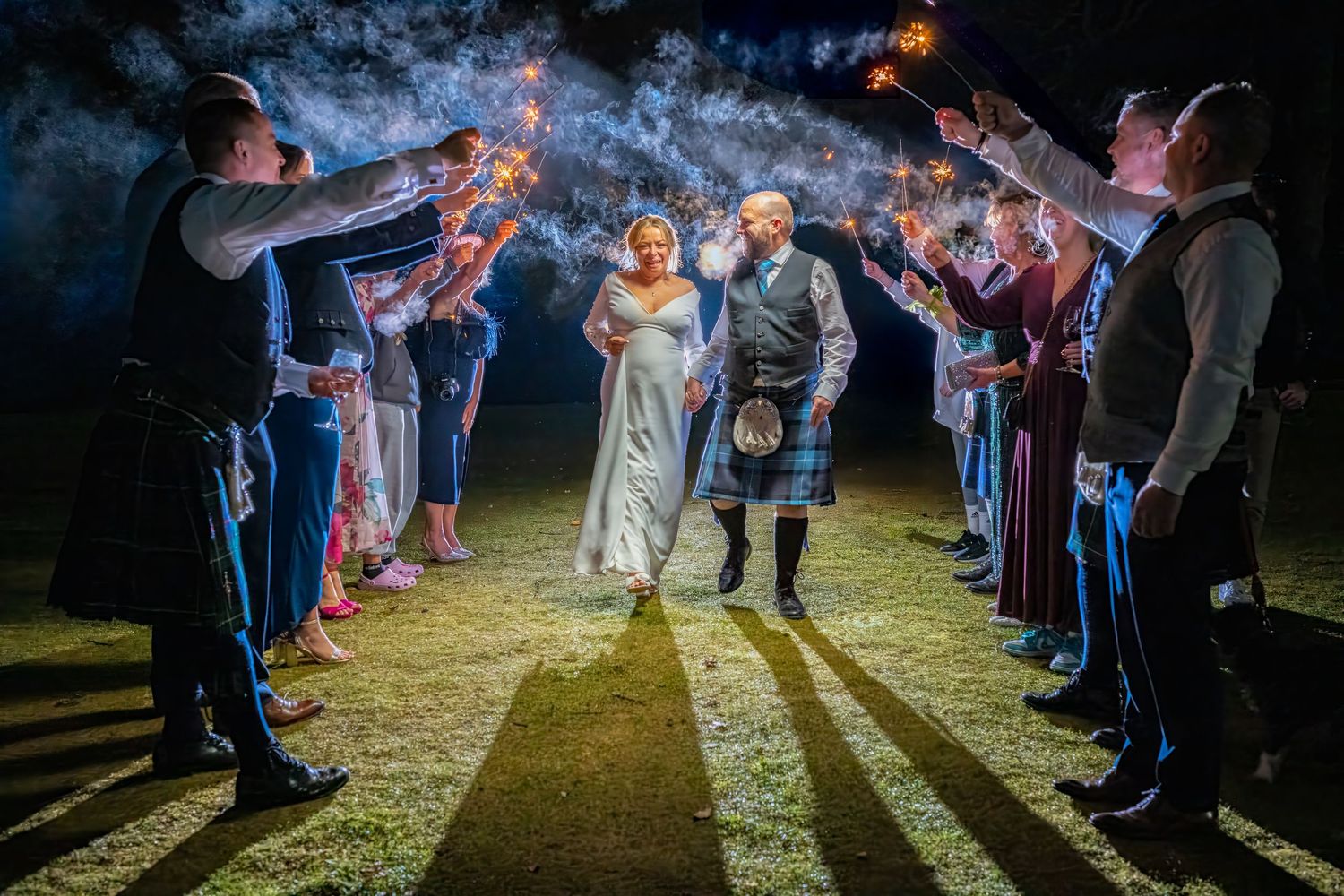 couple walk through tunnel of sparklers on wedding day.